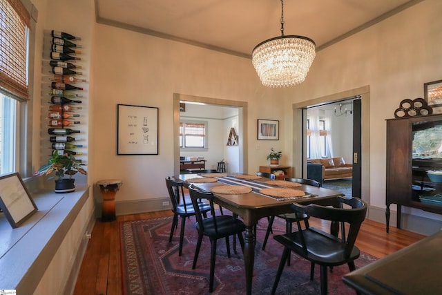 dining room with a notable chandelier, baseboards, wood finished floors, and ornamental molding