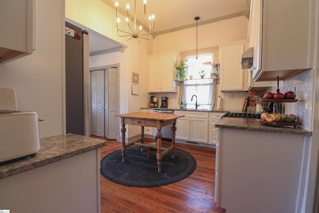 kitchen with tasteful backsplash, white cabinets, dark wood-style floors, decorative light fixtures, and extractor fan