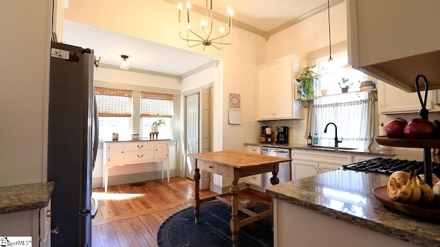 kitchen featuring tasteful backsplash, appliances with stainless steel finishes, ornamental molding, white cabinetry, and a sink