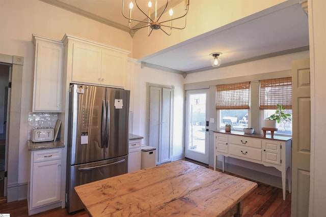 kitchen with white cabinets, dark wood-style floors, dark stone countertops, freestanding refrigerator, and crown molding