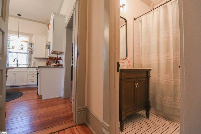 full bath with a shower with curtain, wood-type flooring, crown molding, and vanity