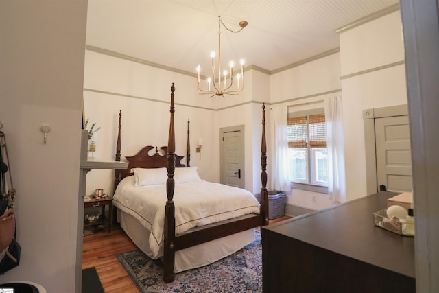 bedroom with a notable chandelier, crown molding, and wood finished floors