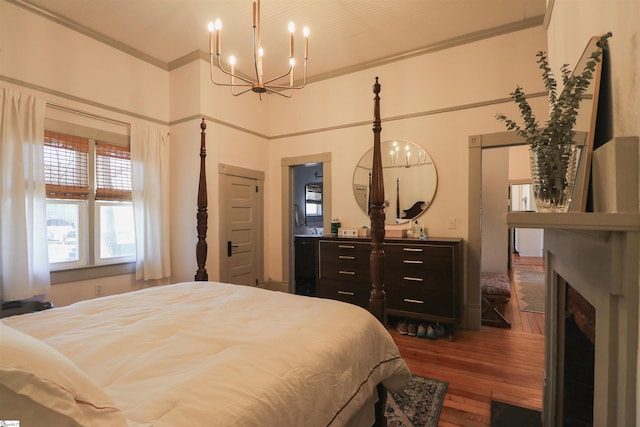 bedroom with dark wood-type flooring, a chandelier, crown molding, and a fireplace