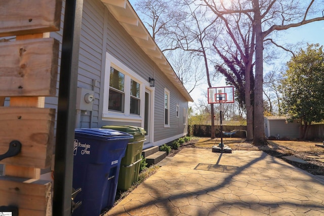 view of property exterior with a patio, an outdoor structure, and fence