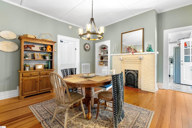 dining area with ornamental molding, visible vents, light wood-style flooring, and built in shelves