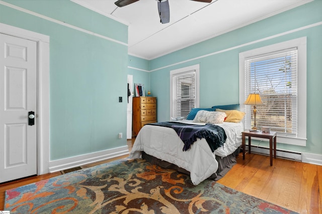 bedroom featuring ornamental molding, a baseboard radiator, baseboards, and wood finished floors