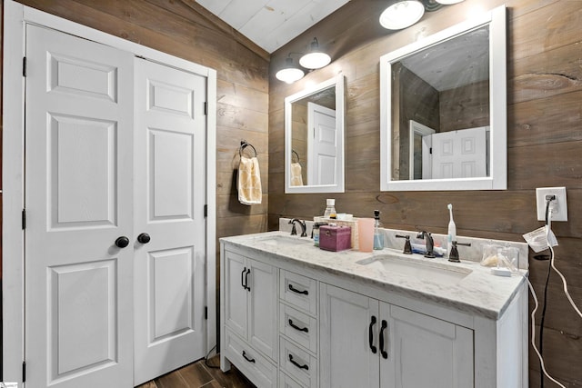 full bathroom featuring wood finished floors, a sink, wooden walls, and double vanity