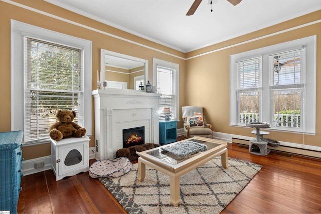 living area featuring crown molding, baseboards, plenty of natural light, and hardwood / wood-style floors