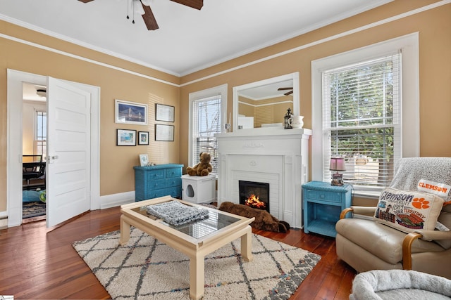 living area with ornamental molding, a brick fireplace, and wood-type flooring