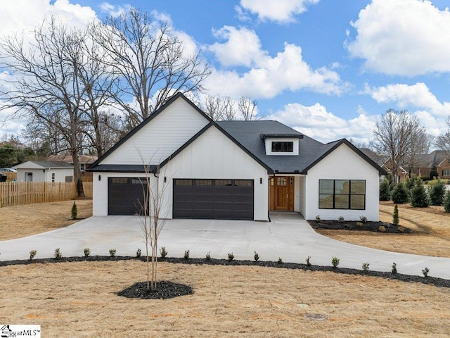 modern inspired farmhouse with a garage, driveway, board and batten siding, and fence