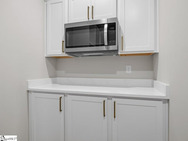 details featuring light countertops, stainless steel microwave, and white cabinets