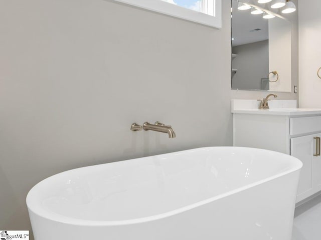 full bathroom with a freestanding tub, visible vents, and vanity