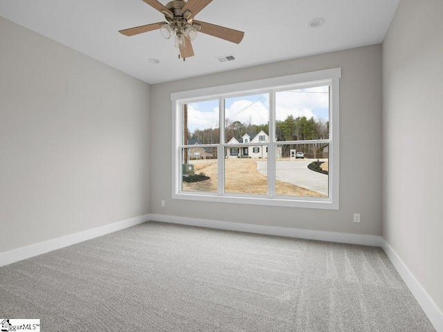 empty room with baseboards, visible vents, a ceiling fan, and light colored carpet