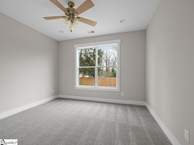 carpeted empty room featuring a ceiling fan, visible vents, and baseboards