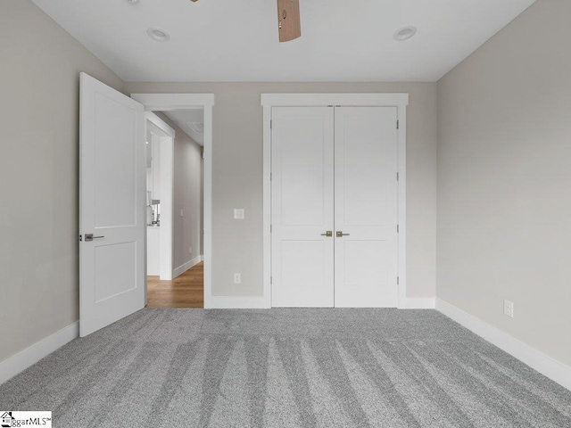 unfurnished bedroom with carpet floors, a closet, baseboards, and a ceiling fan