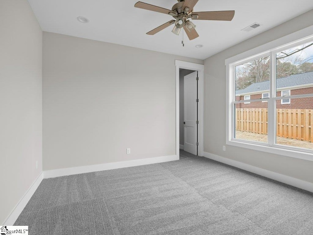 carpeted spare room with visible vents, ceiling fan, and baseboards