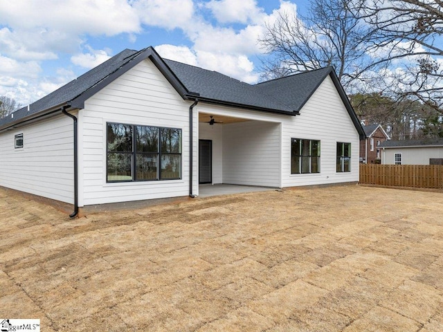 back of property featuring ceiling fan, fence, roof with shingles, and a patio