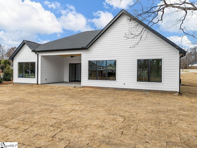 back of house featuring roof with shingles, a lawn, a patio area, and a ceiling fan