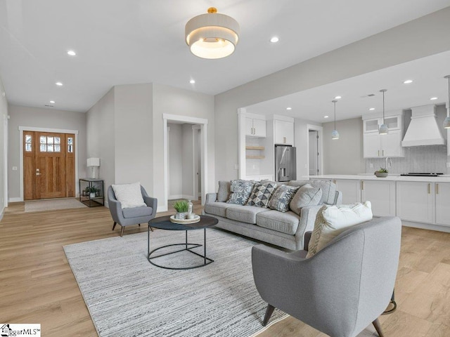 living room featuring baseboards, recessed lighting, and light wood-style floors