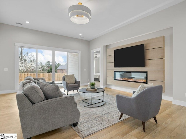 living room with recessed lighting, wood finished floors, visible vents, baseboards, and a glass covered fireplace