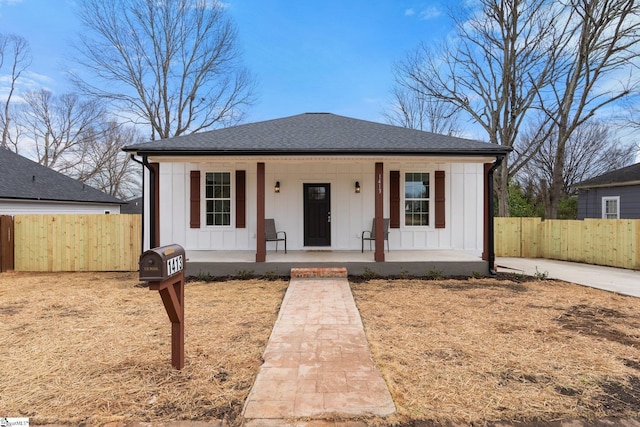 bungalow-style house with a porch, board and batten siding, a shingled roof, and fence