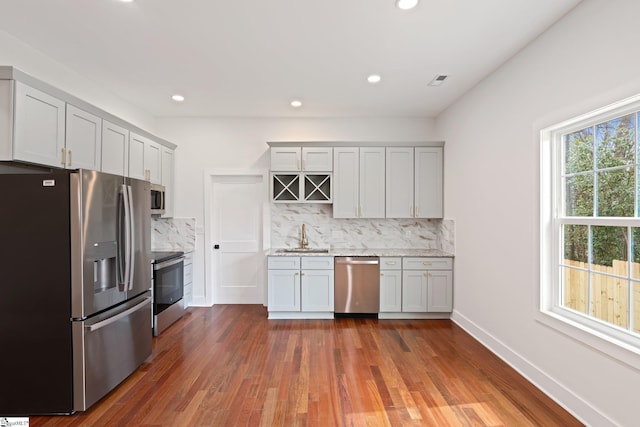 kitchen featuring tasteful backsplash, baseboards, light stone counters, dark wood-type flooring, and stainless steel appliances