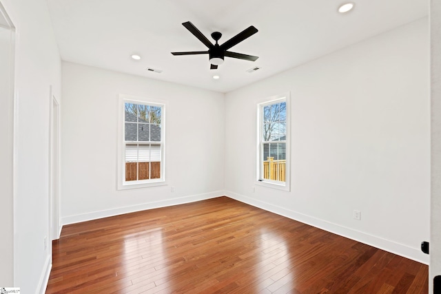 spare room with ceiling fan, hardwood / wood-style floors, visible vents, and baseboards