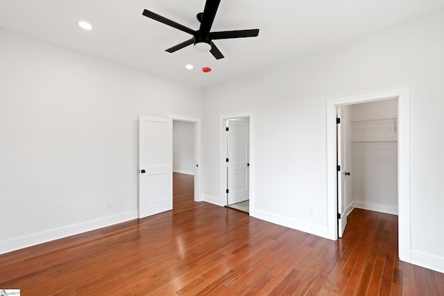 unfurnished bedroom with baseboards, a ceiling fan, wood finished floors, a spacious closet, and recessed lighting