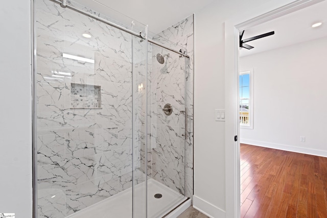 full bath featuring wood finished floors, a marble finish shower, and baseboards