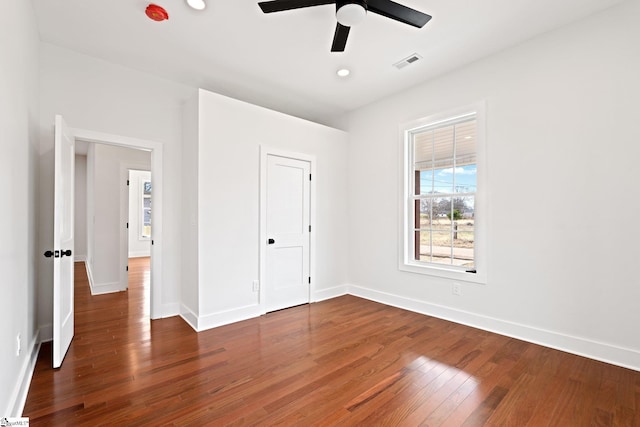 unfurnished bedroom featuring a ceiling fan, baseboards, visible vents, and hardwood / wood-style floors