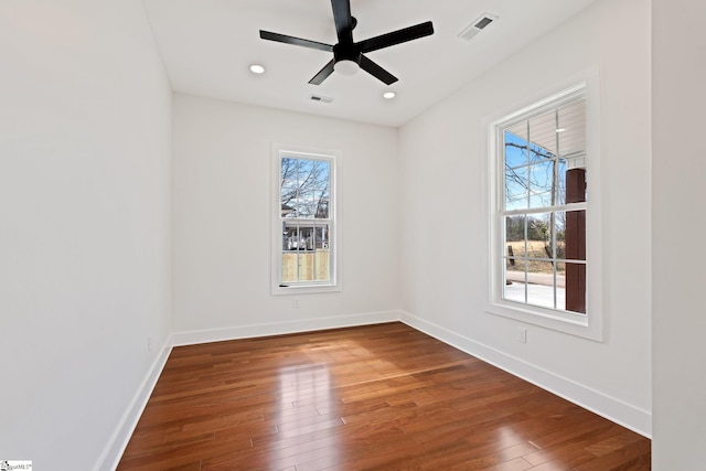 spare room featuring baseboards, visible vents, and hardwood / wood-style floors