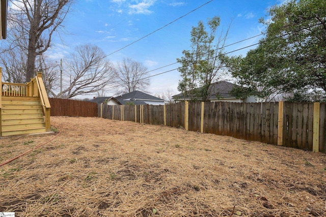 view of yard with a fenced backyard and stairway