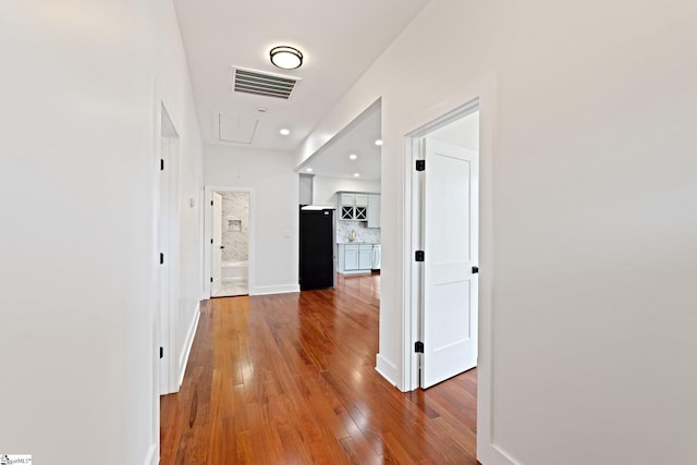 corridor featuring recessed lighting, visible vents, baseboards, wood-type flooring, and attic access