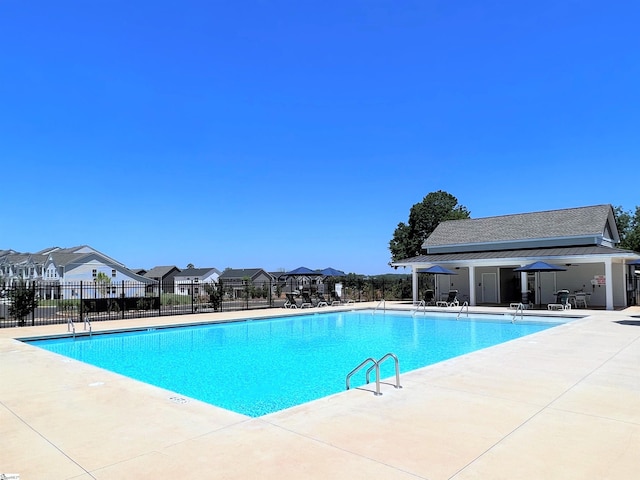 pool featuring fence, a patio area, and a residential view