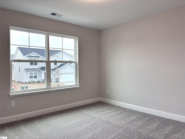 carpeted empty room featuring visible vents and baseboards