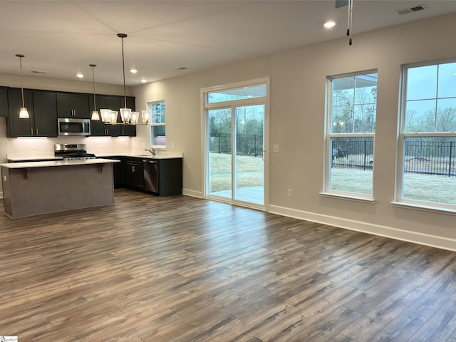 kitchen with open floor plan, stainless steel appliances, light countertops, dark wood finished floors, and visible vents