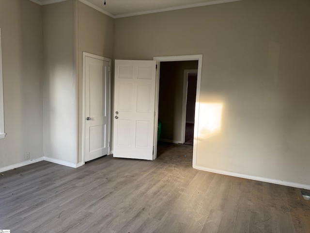 unfurnished bedroom featuring baseboards, wood finished floors, and ornamental molding