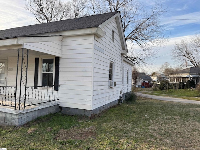 view of property exterior featuring a porch, cooling unit, roof with shingles, and a yard