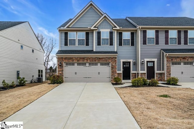 view of front of house featuring an attached garage, stone siding, cooling unit, and concrete driveway