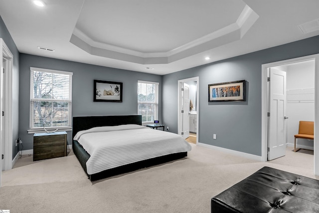 bedroom featuring light carpet, visible vents, multiple windows, and a tray ceiling