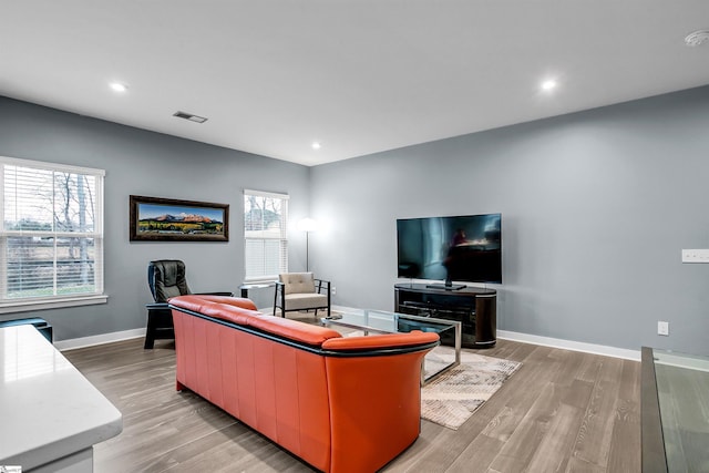 living area with light wood-type flooring, visible vents, baseboards, and recessed lighting