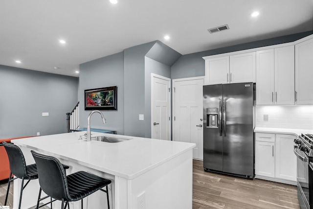 kitchen with light wood-style flooring, a sink, visible vents, gas stove, and stainless steel fridge