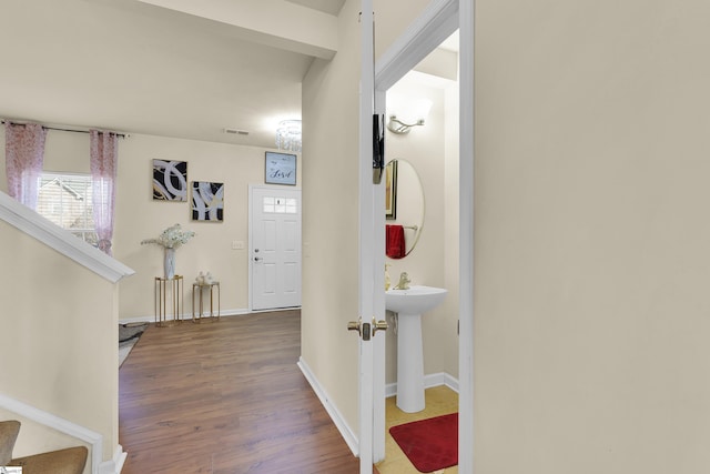 hall featuring baseboards, stairs, visible vents, and wood finished floors