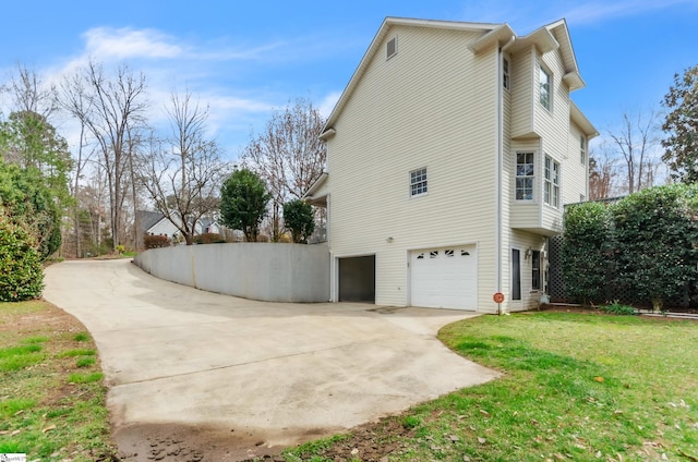 view of side of property featuring concrete driveway, a yard, and an attached garage