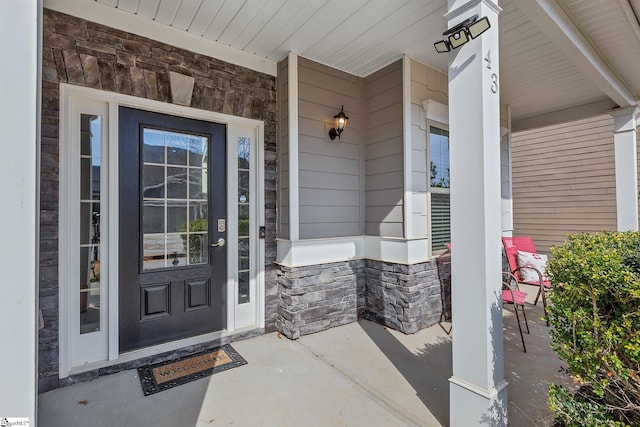 entrance to property with stone siding and a porch