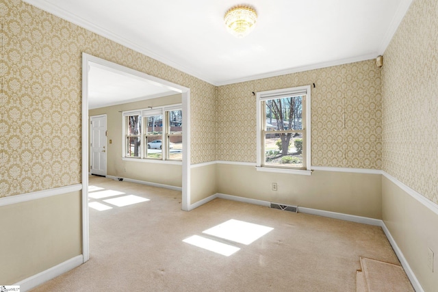 carpeted spare room with visible vents, crown molding, baseboards, and wallpapered walls