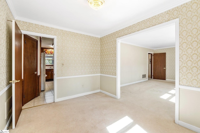 carpeted spare room with wallpapered walls, visible vents, and crown molding