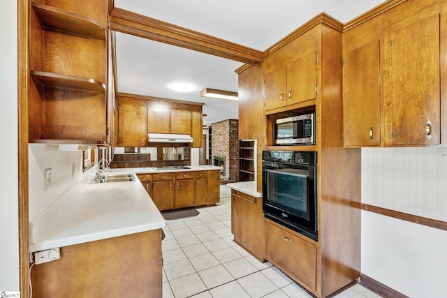 kitchen with brown cabinets, under cabinet range hood, black appliances, open shelves, and a sink