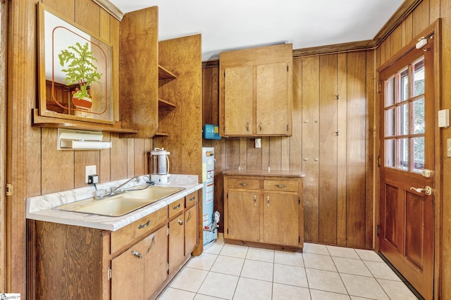 kitchen featuring light tile patterned floors, open shelves, light countertops, a sink, and wooden walls