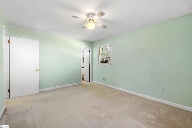 carpeted empty room featuring ceiling fan and baseboards